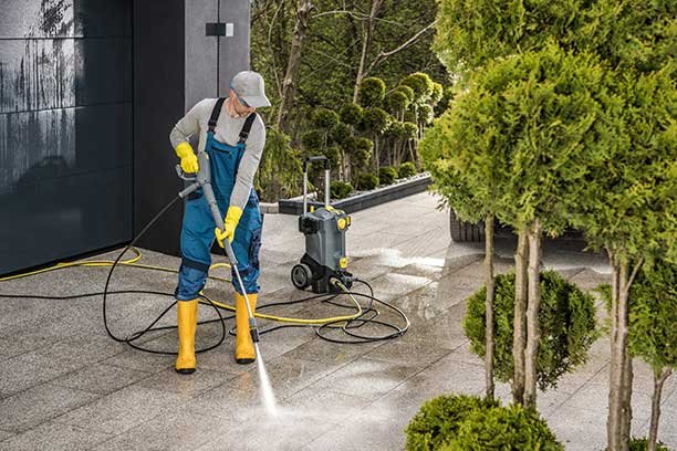 Men Cleaning His Modern House Surroundings with a Powerful Pressure Washer